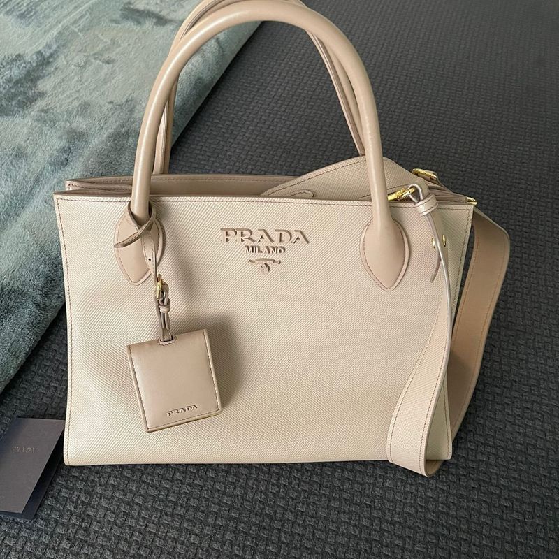 https://photos.enjoei.com.br/bolsa-prada-milano-tote-original-84839304/800x800/czM6Ly9waG90b3MuZW5qb2VpLmNvbS5ici9wcm9kdWN0cy8xMjg3MjI5MS9iNjUwMDhlYzg1MTQ4YzQ4MDliNTJmNDcwZGZhMzg2Zi5qcGc