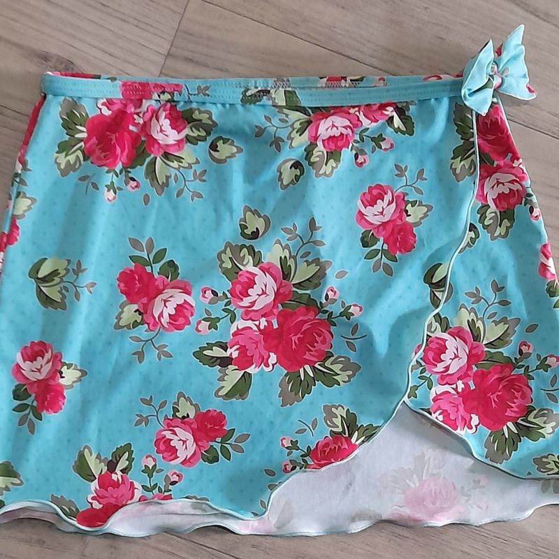 Uma roupa de menina com um top verde e rosa e uma saia.